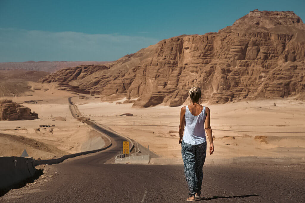 woman walking along a road in the desert