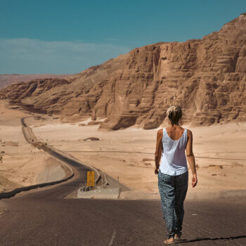woman walking along a road in the desert