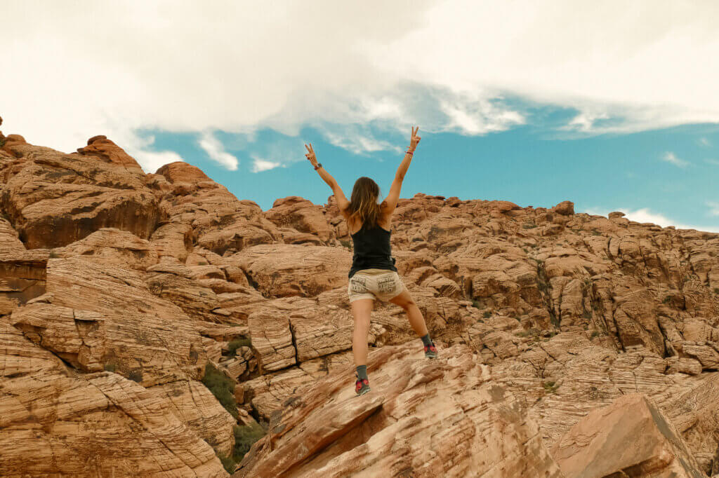 A woman hiking and showing victory with her hands to go with this blog post about overcoming people pleasing and learning to set boundaries